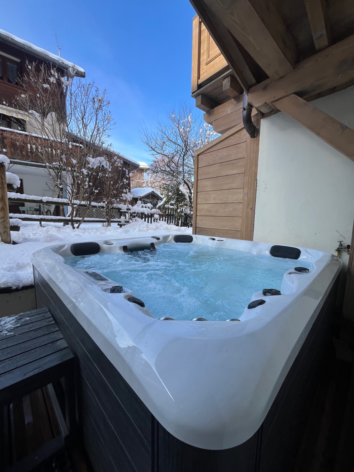 Outdoor hot tub running in the snow beside a chalet